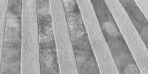 Close-up of a striped carpet with alternating light and dark shades.