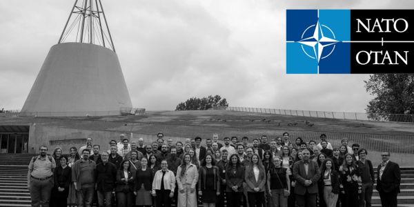 Group photo of NATO members in front of a modern building.