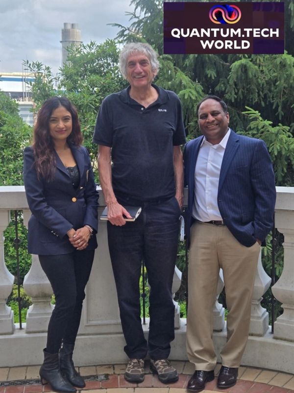 Three professionals posing outdoors with a Quantum.Tech World banner.