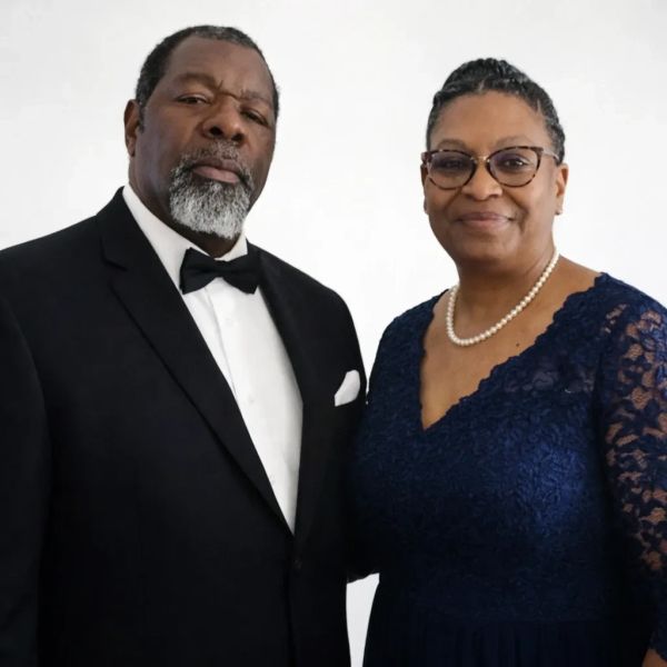 A formally dressed couple posing against a white background.