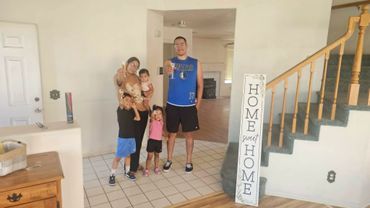 A family of five posing together in their home foyer.
