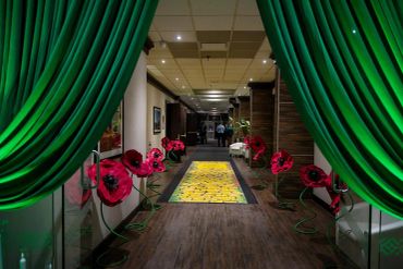 A hallway decorated with large red flowers and green curtains.