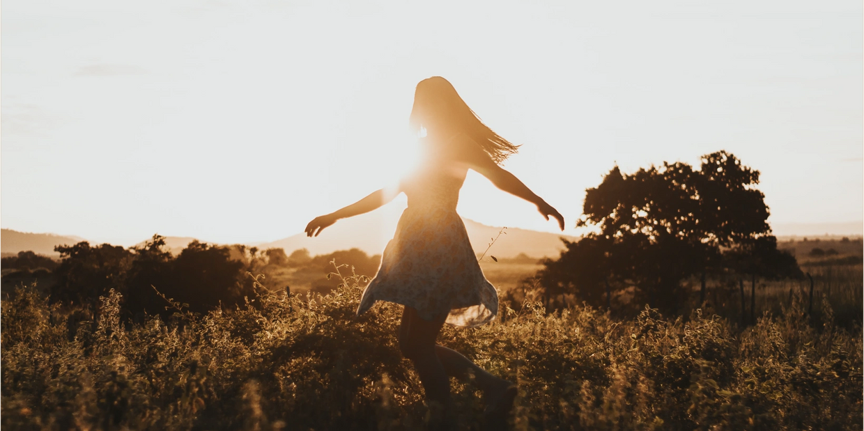 Woman frolicking in field at dusk. Fulfillment resilience empowerment happiness healing therapy