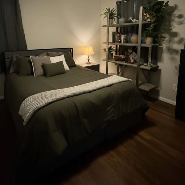 Cozy bedroom with green bedding and warm lighting.