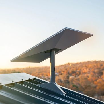 Solar panel mounted on a metal roof at sunset.