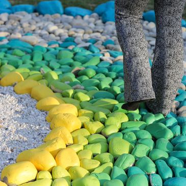 Legs walking on colorful painted stones arranged in a gradient pattern.