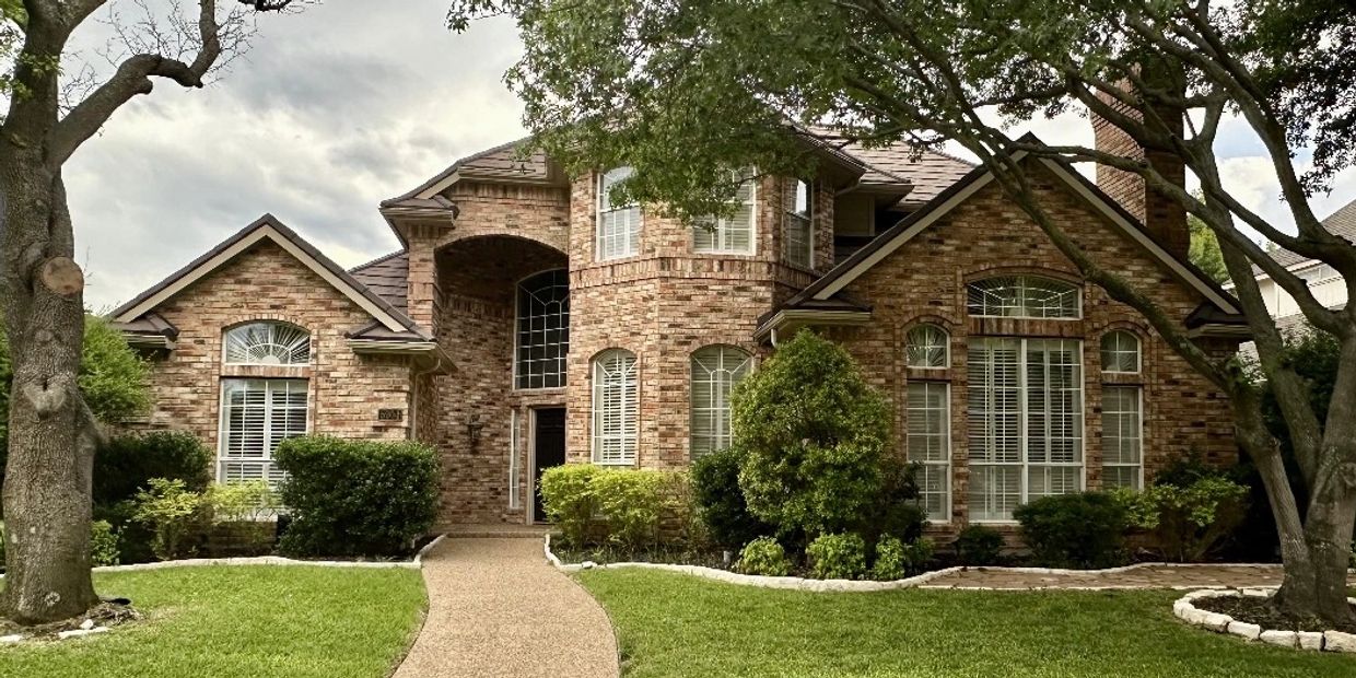 Elegant brick house with arched windows and lush landscaping.