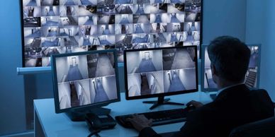 A person monitors multiple surveillance camera feeds in a control room.