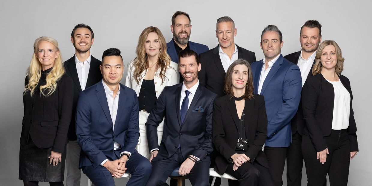 A diverse group of eleven professionals posing together in business attire.