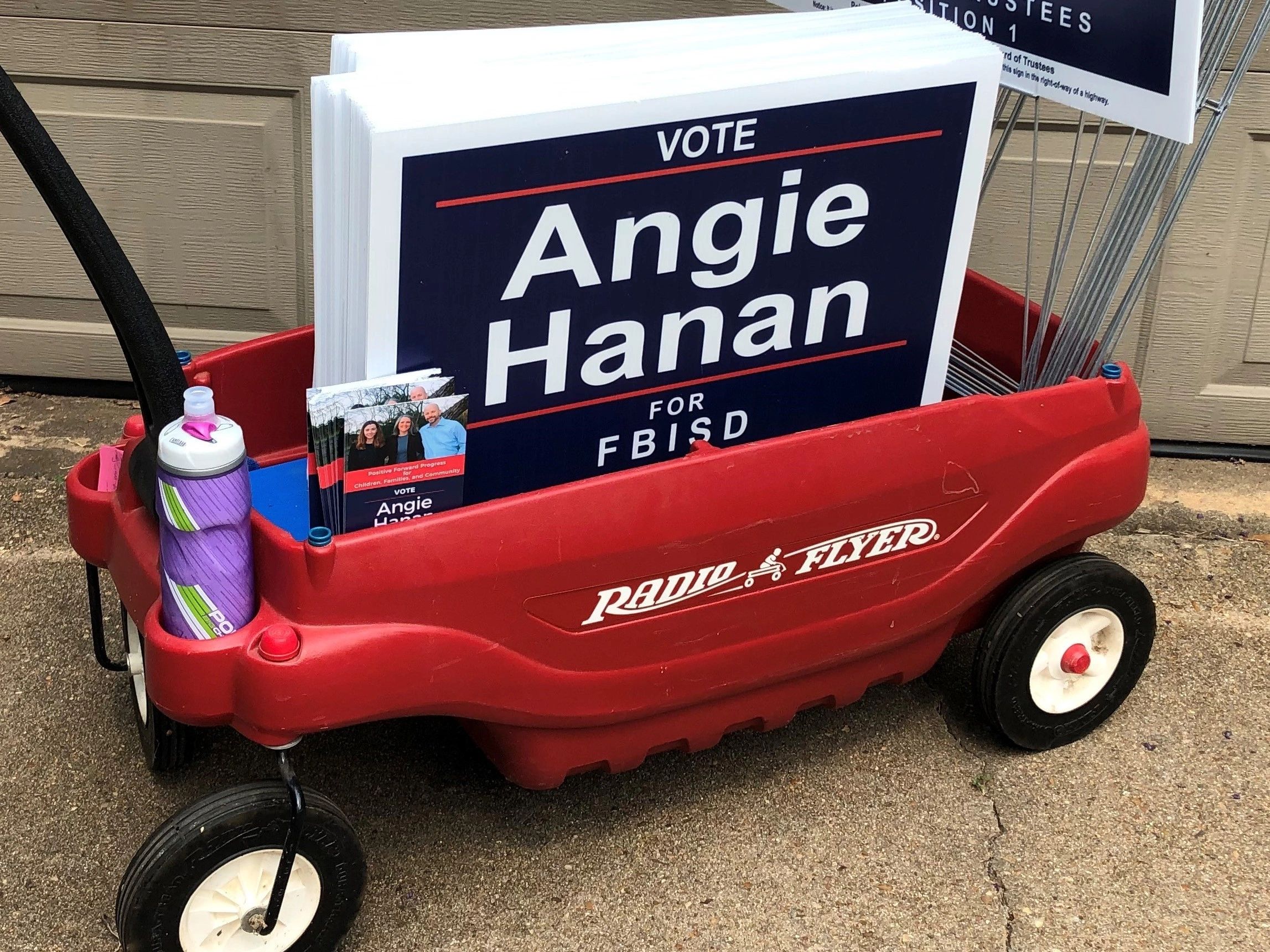 Red Radio Flyer wagon holding campaign signs for Angie Hanan.
