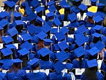 Students wearing blue caps at graduation.