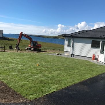 Newly laid green lawn near a house with a scenic water view.