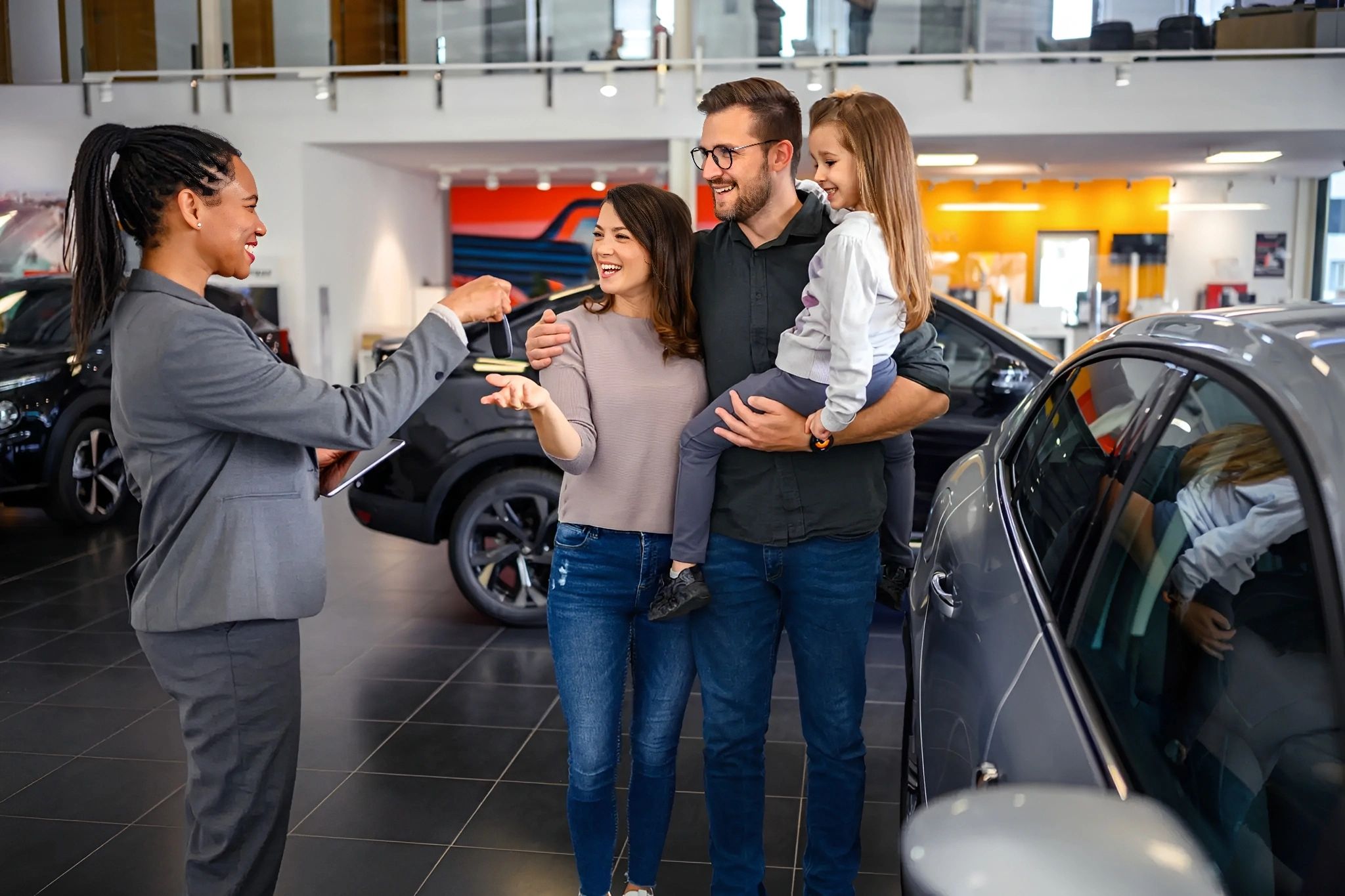 Dealer hands keys to family with child.