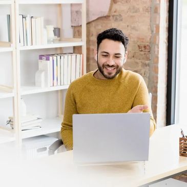 teacher in orange sweater teaching to a laptop in front of him