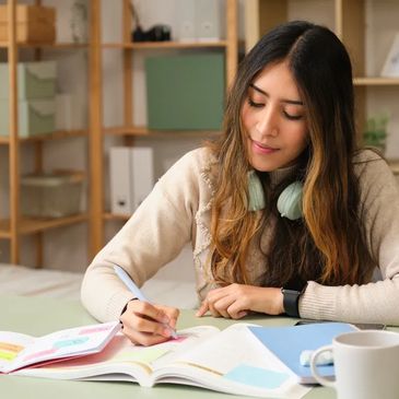 girl with headphones around her neck studying and making notes