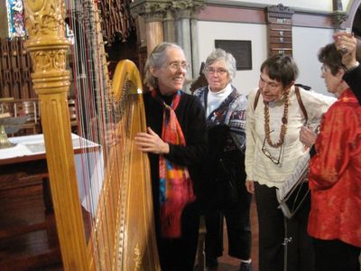The harpist from a recent musicale describes her instrument to audience members.