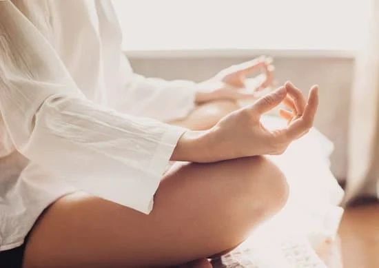 person sat meditating in white shirt