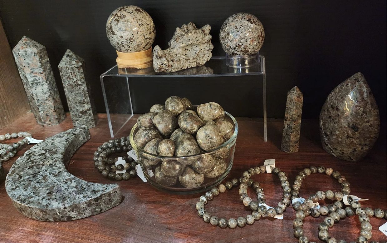 Polished granite stones, spheres, and jewelry displayed on a wooden surface.