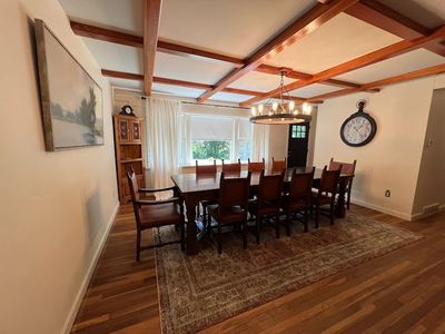 Elegant dining room with a long wooden table, chairs, and vintage chandelier.