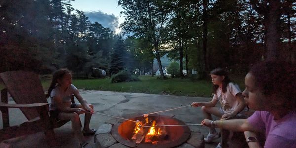 Children roasting marshmallows around a fire pit at dusk. Lake View Airbnb