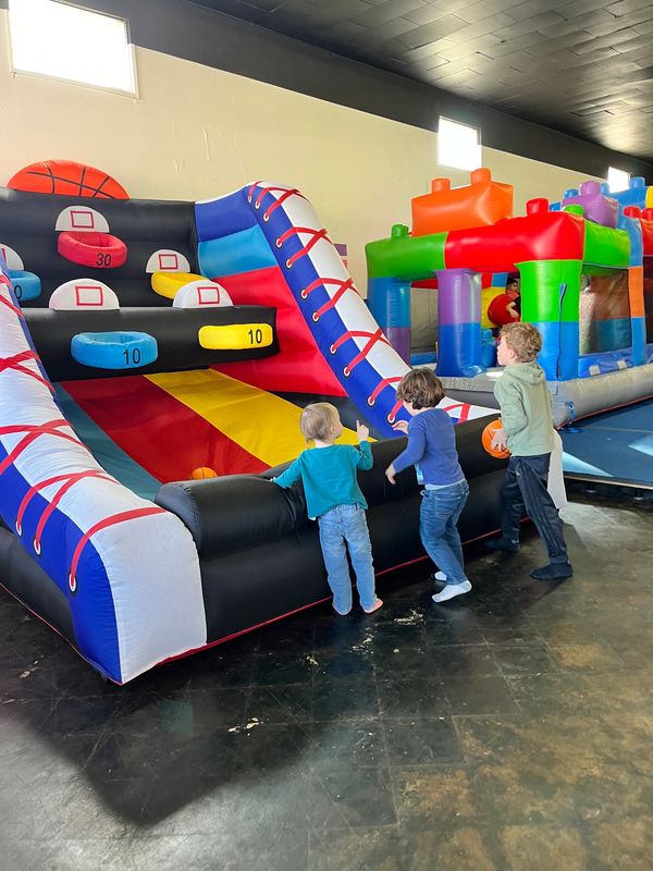 Three kids playing on indoor inflatable basketball game.