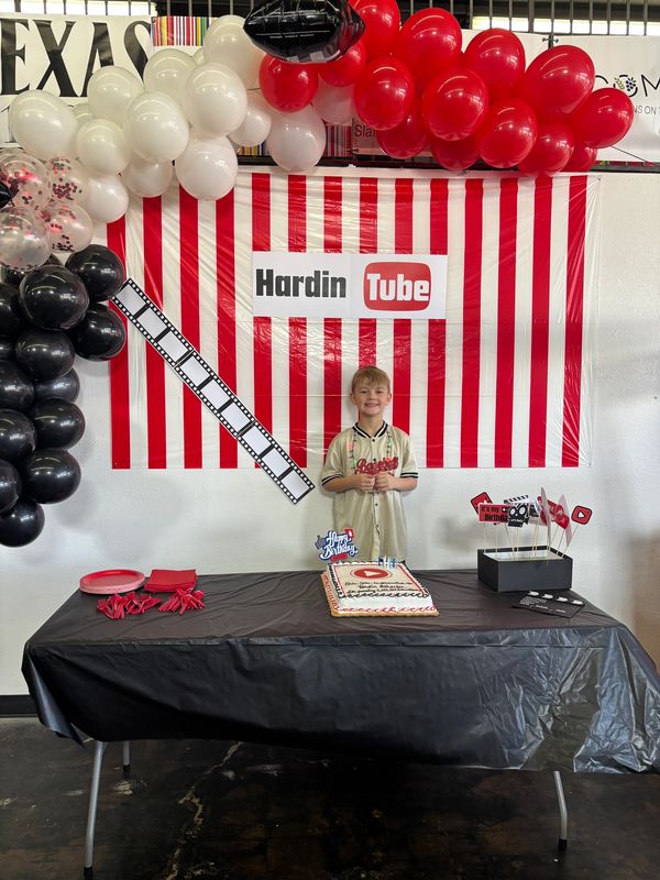 Young boy celebrating birthday with YouTube-themed party decorations.