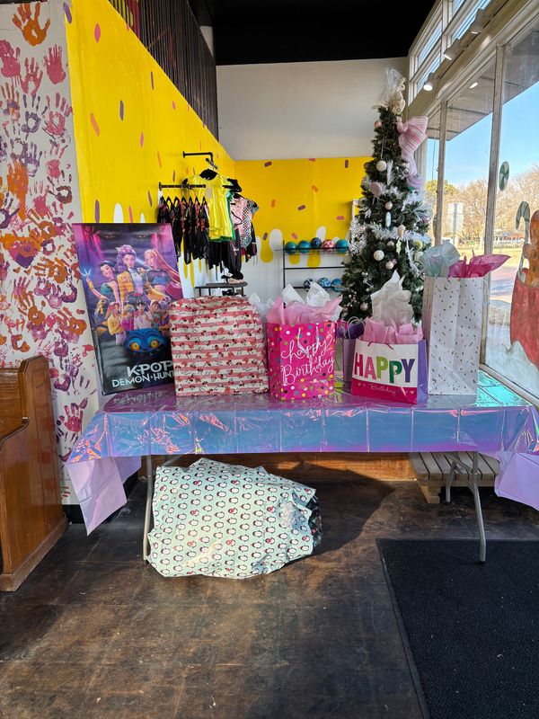 Birthday gifts on a decorated table next to a Christmas tree.