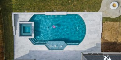 Aerial view of a modern backyard pool with a child floating.