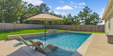 Backyard swimming pool with lounge chairs and umbrella.