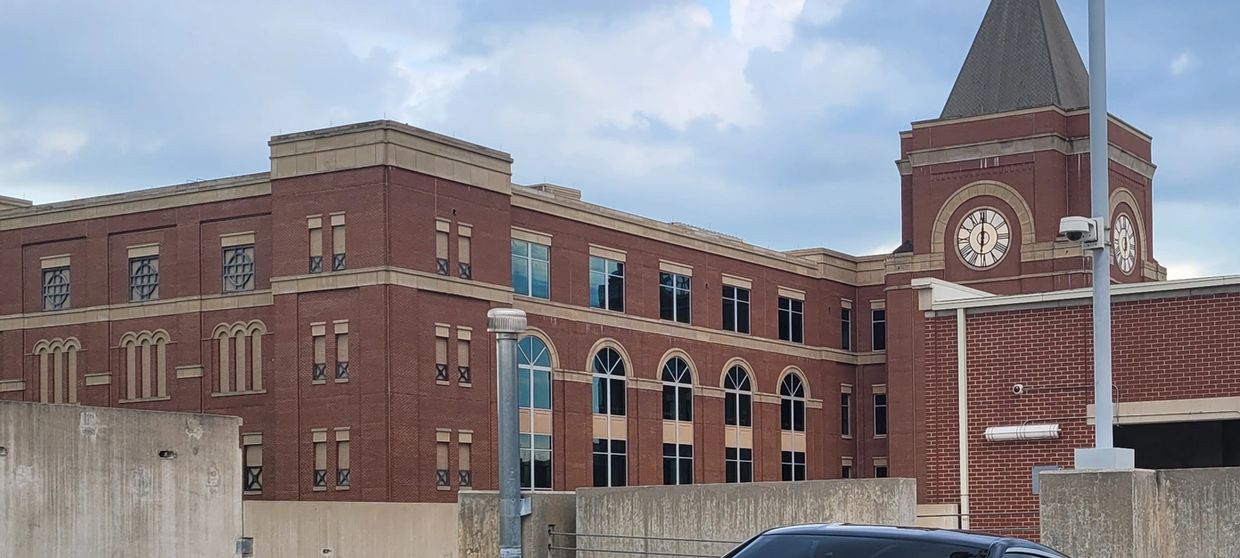 Brick building with a clock tower and parked car.