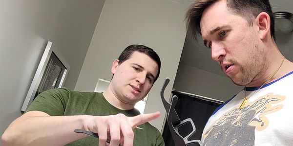 Two men closely examining an object in a room.