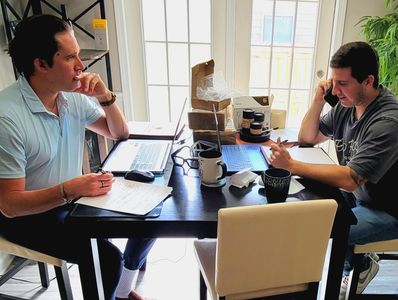Two men working and discussing at a table.