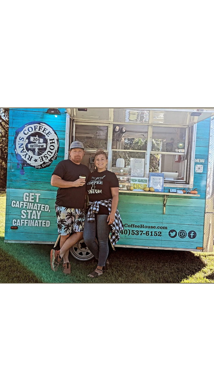 Ryan and Krista owners of a mobile coffee shop stand in front of their trailer drinking lattes