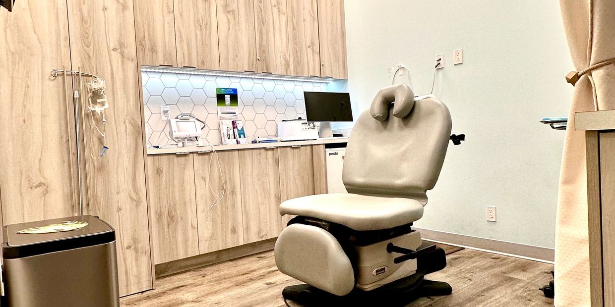 Modern medical examination room with wooden cabinets and a reclining chair.