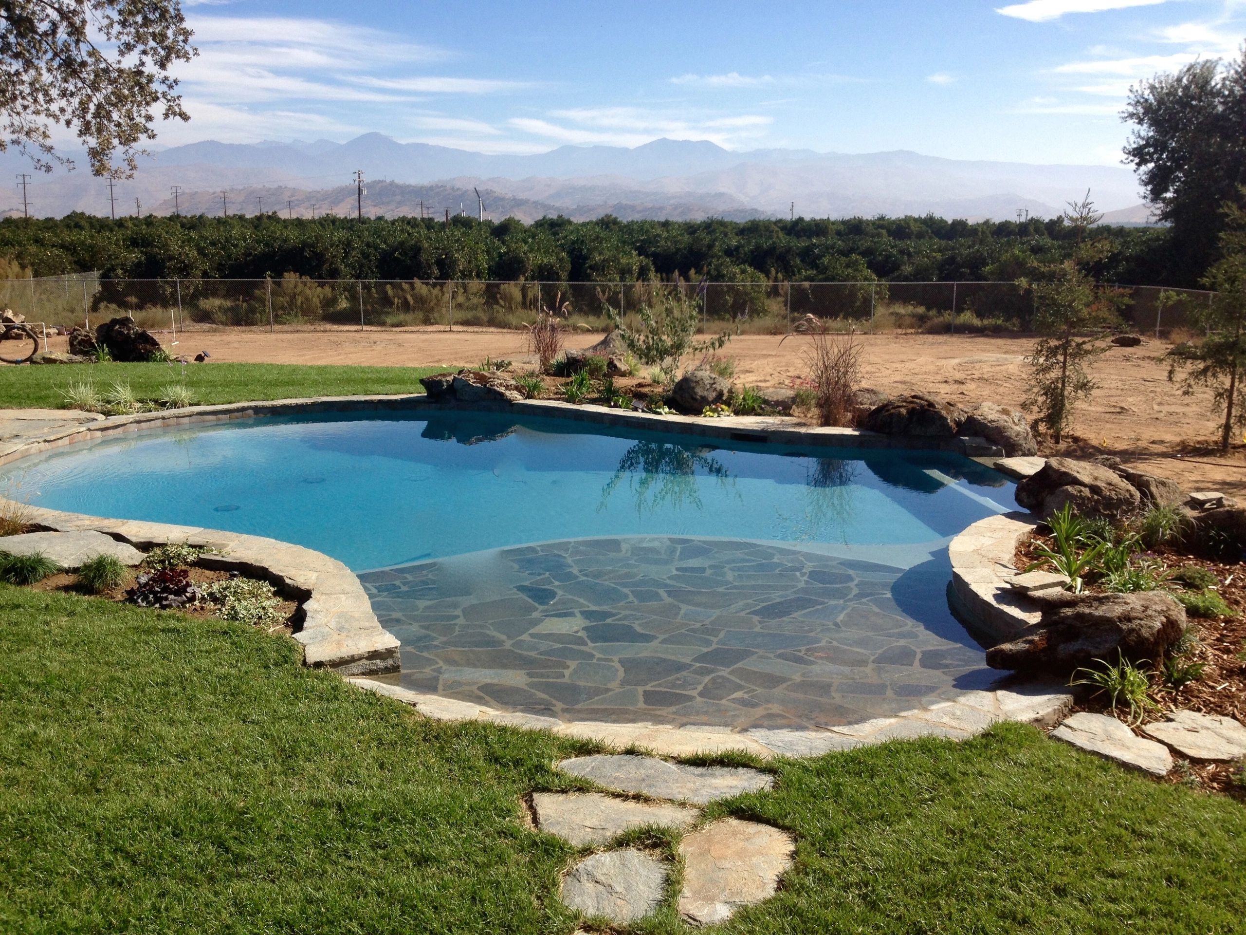 A serene backyard pool with stone accents and mountain views.