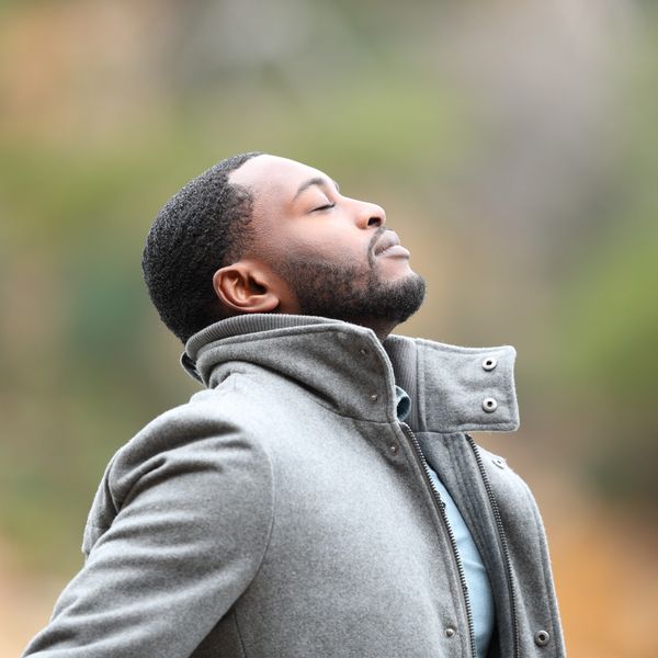 Relaxed man with black skin in winter breathing fresh air outdoors