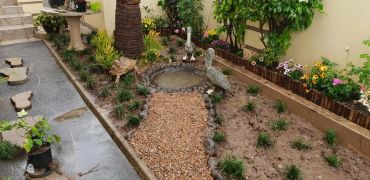 Small garden with plants, gravel path, and stone ornaments.