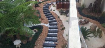 Curved garden path with dark stones and white accents.