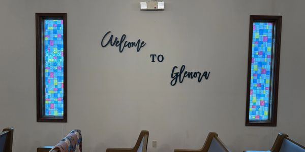 Wall decor saying 'Welcome to Glenora' with colorful stained glass windows.