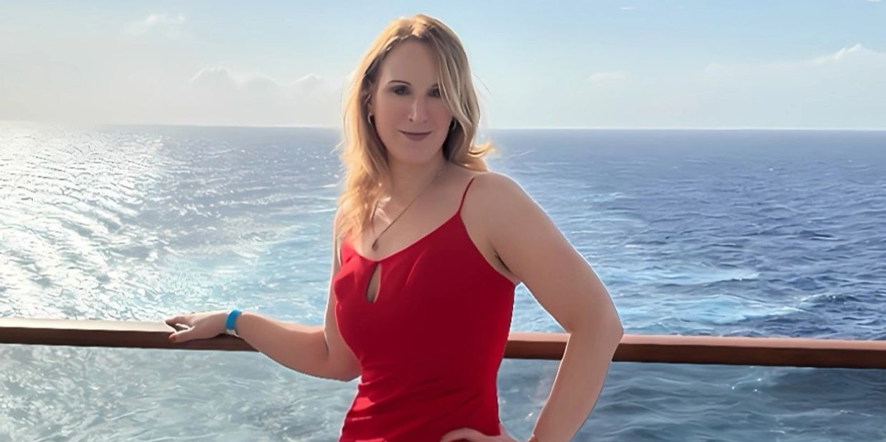 Woman in a red dress posing by the ocean on a boat.