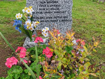Gravestone of Kristen Kenneth Crouch adorned with colorful flowers in a serene cemetery.