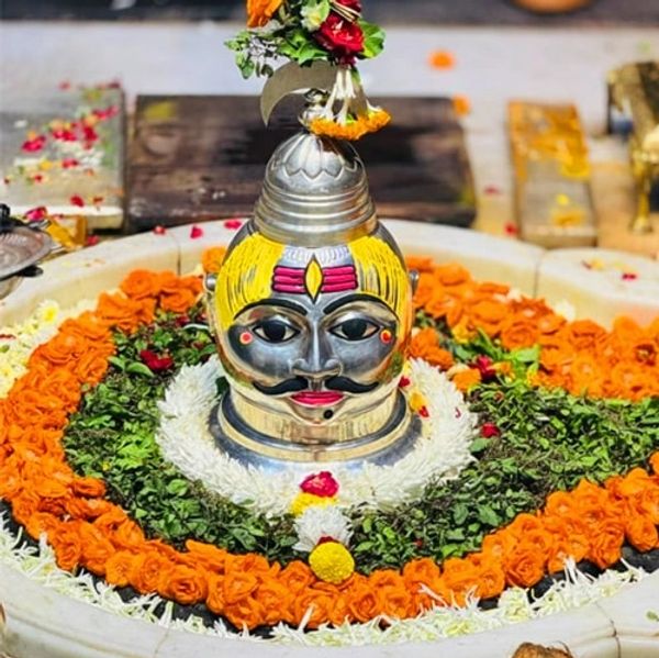 Decorated Shiva Lingam with flowers in a ceremonial setting.