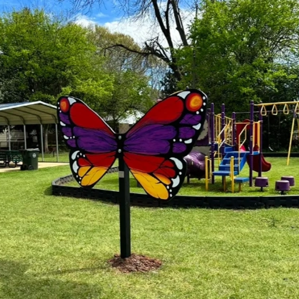 Colorful butterfly sculpture in a park playground.