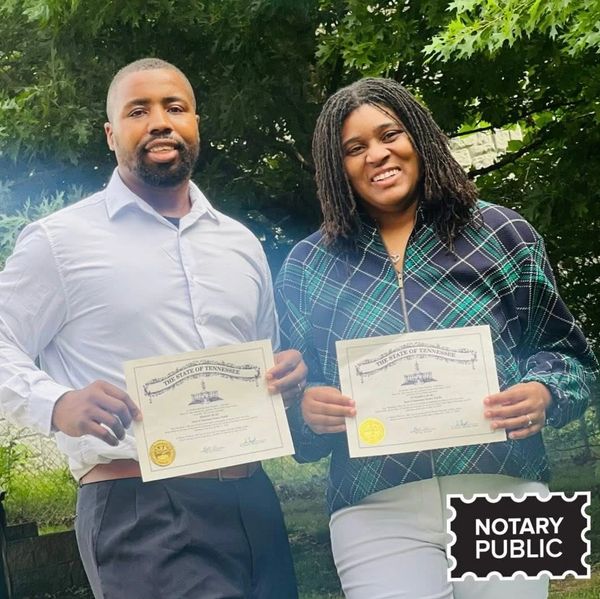 Two people proudly holding Tennessee notary public certificates outdoors.