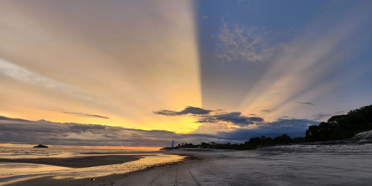 Sunset with rays casting shadows over a beach.