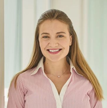 Vrolijke vrouw met lang haar en roze blouse.
