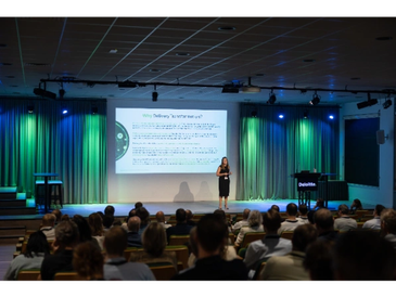 Een vrouw geeft een presentatie voor een publiek in een auditorium.