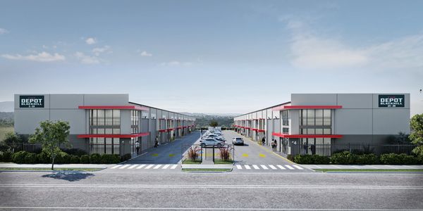 Modern industrial warehouse complex with parking and clear signage.