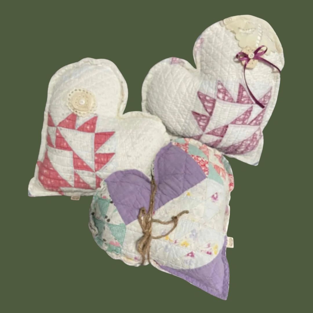 Three quilted heart-shaped decorative pillows with varied pastel patterns.