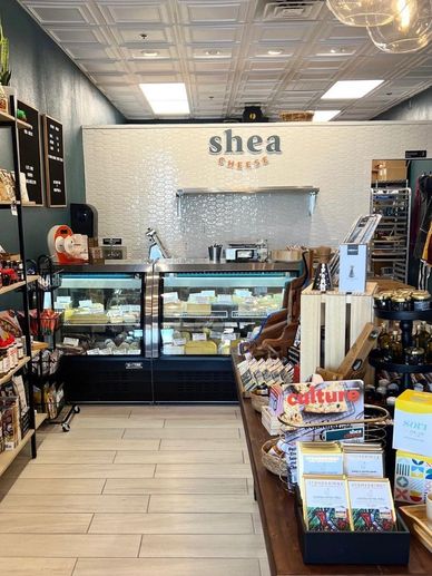 Cheese shop interior with cheese displays and shelves of gourmet products.